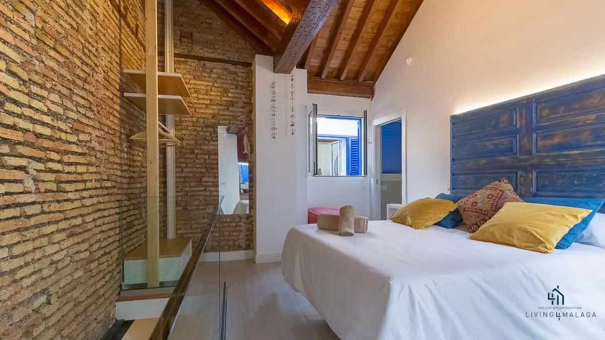 Dormitorio con ladrillo visto y techo de madera